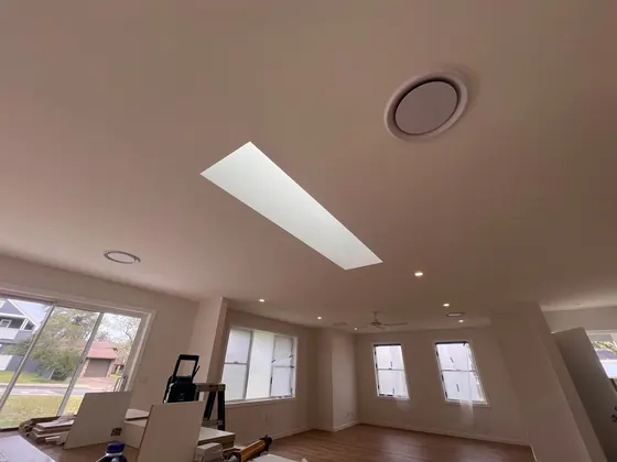 Supply and return vents set into a raked ceiling next to a skylight.