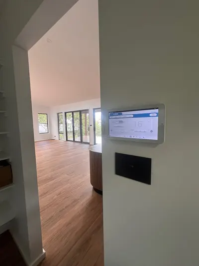 Wall-mounted touchscreen controller for a ducted system in a hallway.