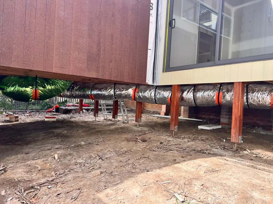 Insulated flexible ducting run through the subfloor of a raised house.