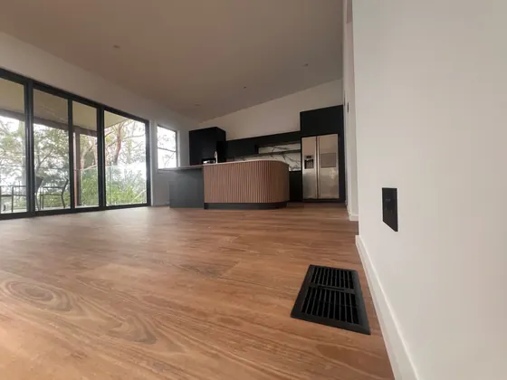 Open-plan living and kitchen with floor supply outlets from a ducted system.