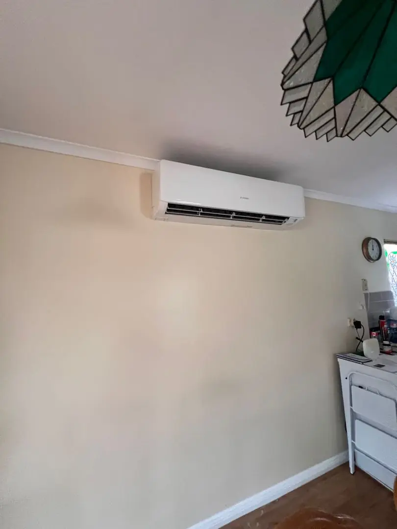 Wall-mounted split system head unit installed high on a living room wall.